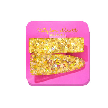 Two yellow glitter hair clips on a pink card