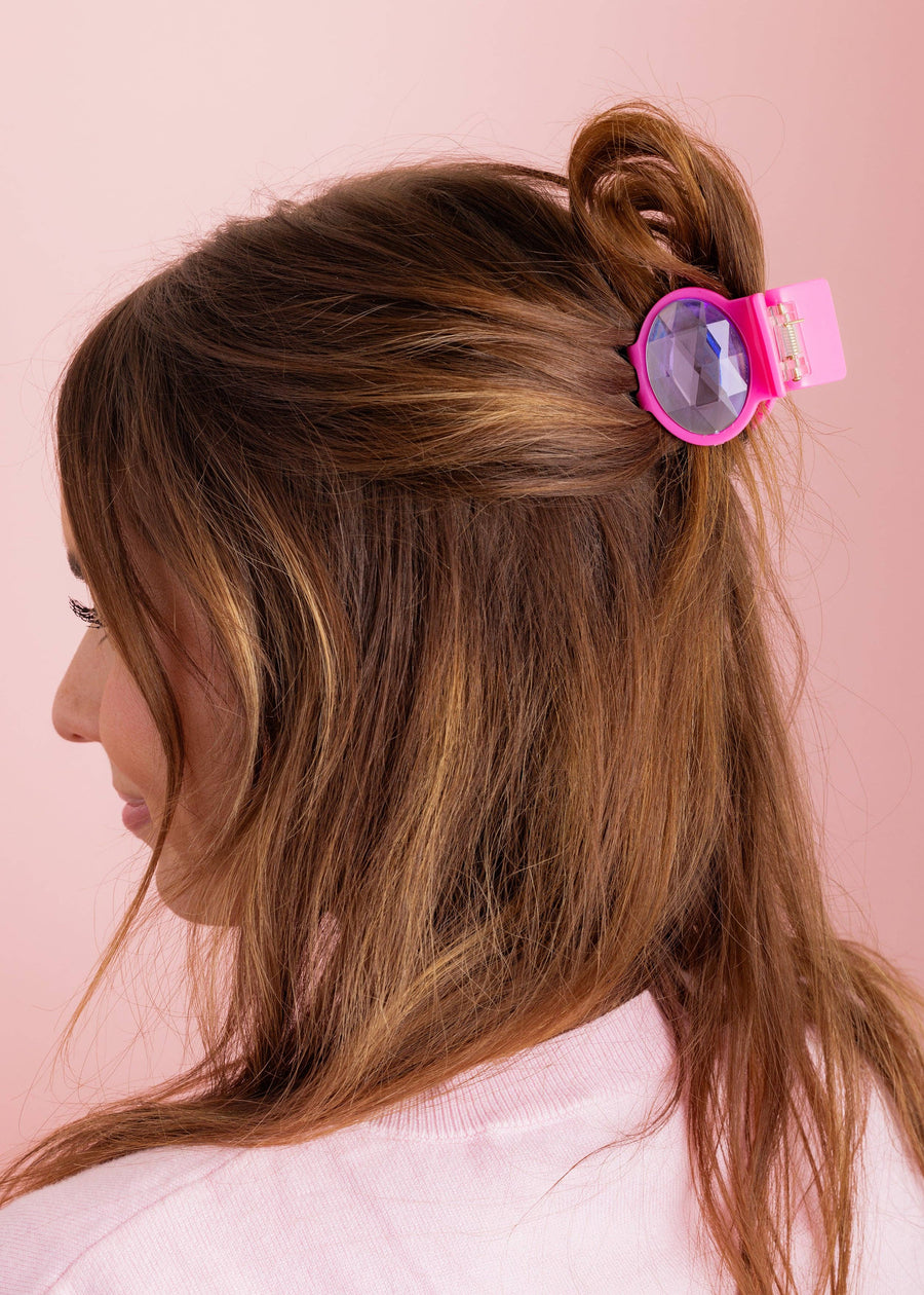 Person with a pink hair clip in their hair against a pink background