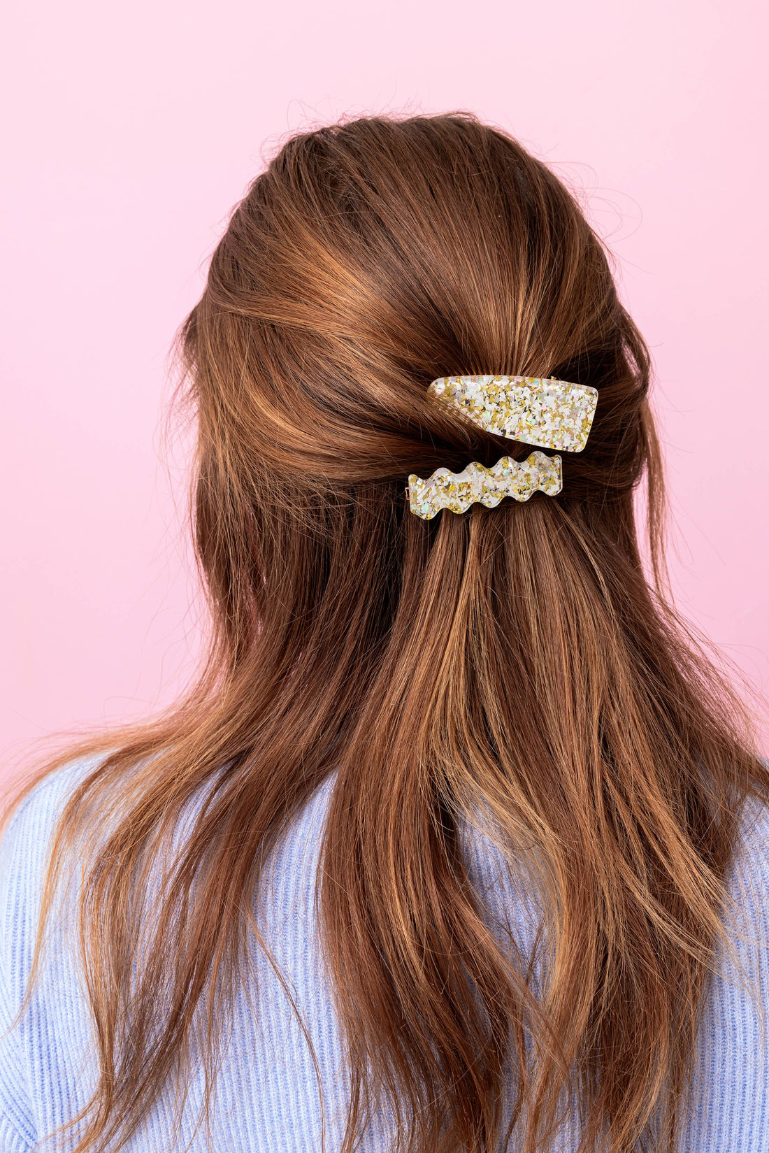 Long brown hair with decorative hair clips on a pink background