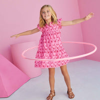 Young girl hula hooping in a babydoll pink eyelet dress with flutter sleeves. 