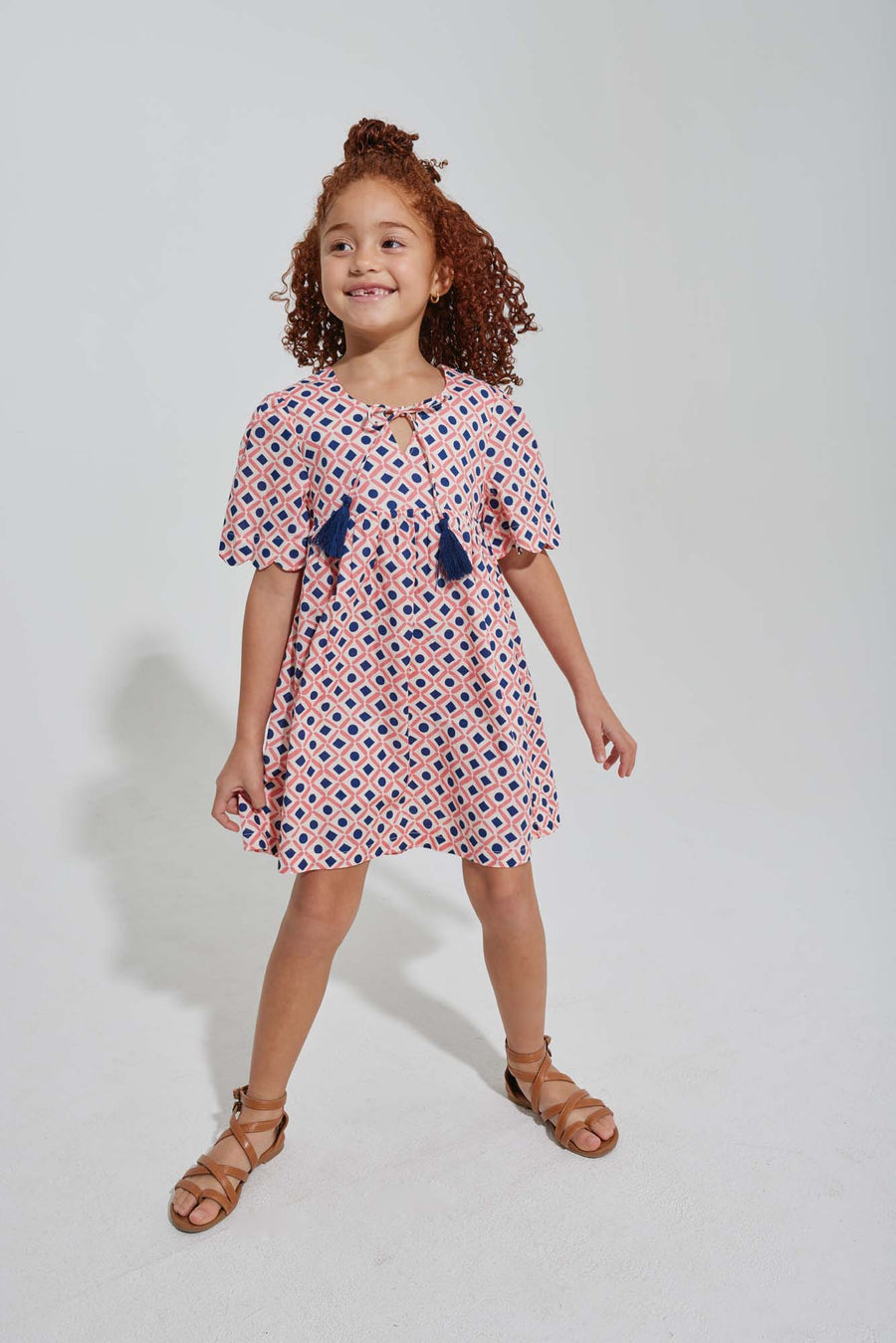 tween girls pink and navy geo print dress with scalloped sleeves and navy tassels