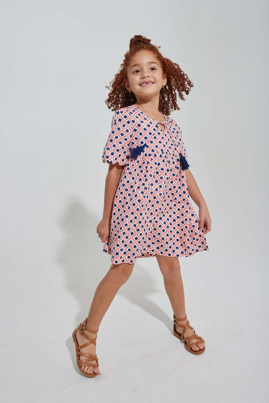 tween girls pink and navy geo print dress with scalloped sleeves and navy tassels